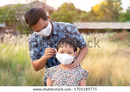 Father help his daughter wearing medical mask for protect 2019 - nCov , covid 19 or corona virus.
