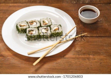 Rolls with salmon and dill on a white plate and soy sauce.