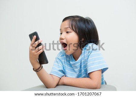 Girl kid using smartphone isolated on white background, looking at mobile phone screen and get shocked with surprise information on internet or social network. Royalty-Free Stock Photo #1701207067