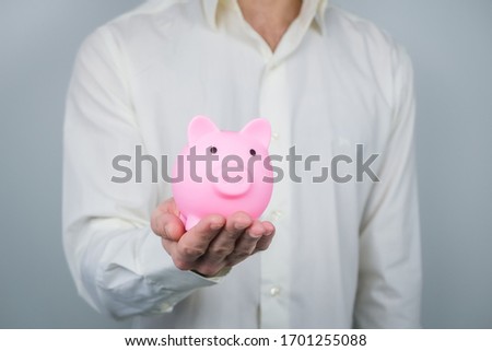 Pink piggy bank in mans hands. Concept of saving and earning money, investments. 
