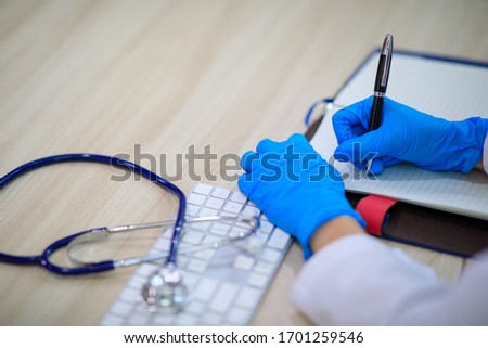 Closeup shot of a Female doctor wearing glove  writhing a report of diagnostic