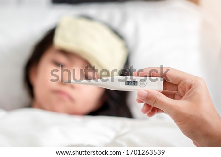 Asian mother holding digital thermometer  with high temperature for check health her daughter, Sick child have cool towel for reduce high fever, Hand focus, Healthy and infection concept Royalty-Free Stock Photo #1701263539