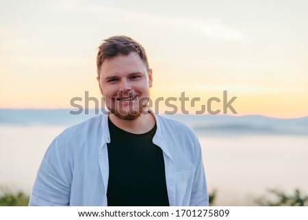 portrait of smiling beard man sunrise in mountains on background