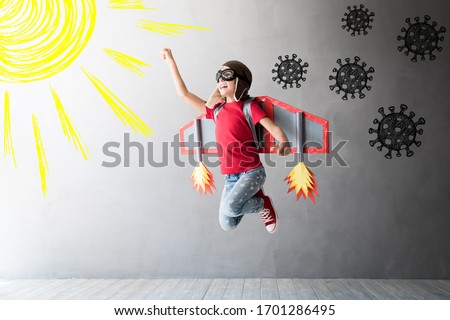 Happy child jumping with toy cardboard wings. Kid pilot flying away from covid virus. Sun and vitamin D concept Royalty-Free Stock Photo #1701286495