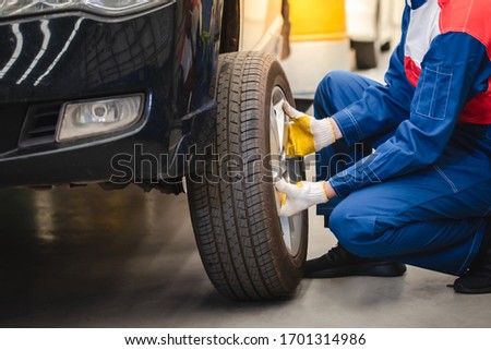 Asian car mechanic is removing the wheel and checking the brakes and suspension in the car service with a forklift. Repair and maintenance center
