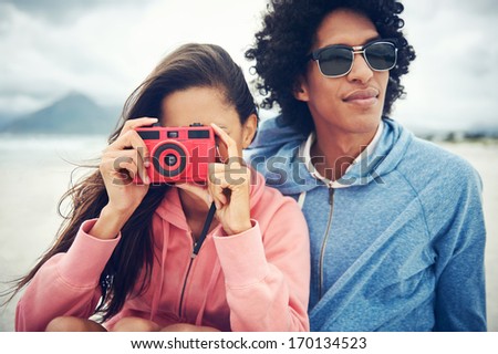 Fashionable hipster couple taking retro camera photo at beach