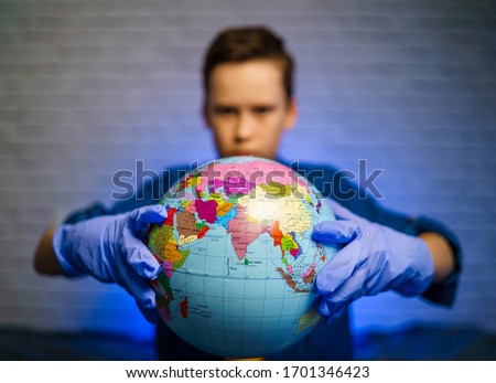 Boy is holding a globe, a model of the planet Earth. Boy is careful of the virus. Pandemic. Coronavirus. COVID-19