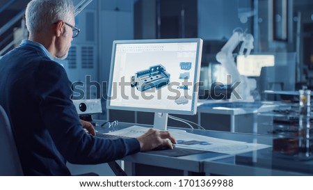 Professional Heavy Industry Engineer Works on Computer Uses CAD Software to Design 3D Industrial Machinery Component. In the Background Robot Arm Concept. Over the Shoulder Shot