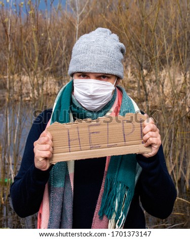 Coronavirus Covid-19 Crisis Quarantine. A desperately scared and angry masked woman. Signature - help. Economics crisis in the time of Covid 19 virus outbreak. Royalty-Free Stock Photo #1701373147