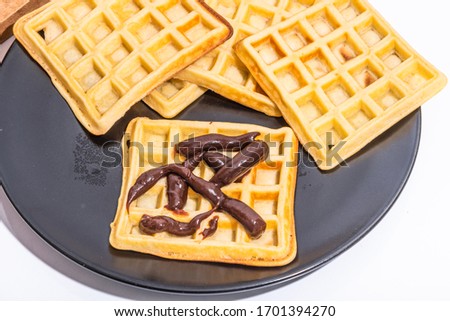 Belgian homemade waffles with chocolate sauce on a black plate
