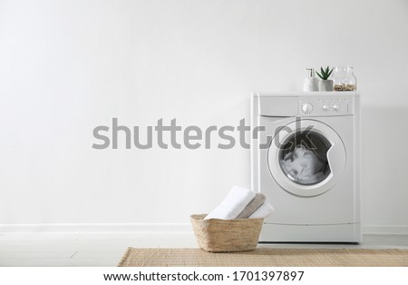 Modern washing machine and laundry basket near white wall indoors, space for text. Bathroom interior Royalty-Free Stock Photo #1701397897