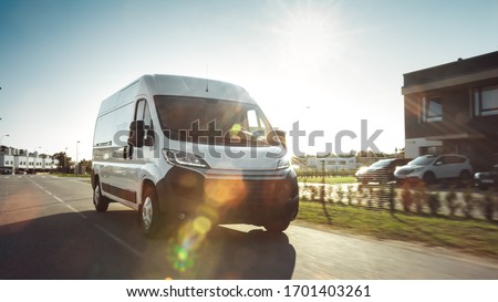 New Delivery Van / Truck Driving Through the Beautiful Suburban Town Area. Postal Delivery Service. Front View Shot Royalty-Free Stock Photo #1701403261