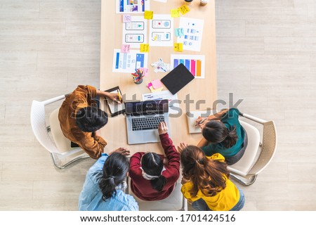 Young Asian business creative team work together using laptop computer, mobile application software design project. Brainstorm meeting, internet technology, office coworker teamwork concept. Top view Royalty-Free Stock Photo #1701424516
