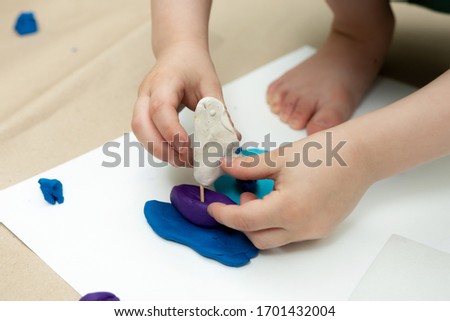 a small child sculpts a sailboat from plasticine. self-isolation classes