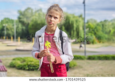 Outdoor portrait of 9, 10 year old blonde child gir, park, sky in clouds background