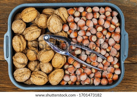 Inshell walnuts and hazelnut, view from the top, on wooden background