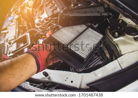 Mechanic hand is replacement car air filter into the filter socket of a car engine,Automotive part concept. Royalty-Free Stock Photo #1701487438