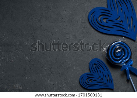Classic blue two hearts and a candy Lollipop on a dark background. Horizontal arrangement. The view from the top