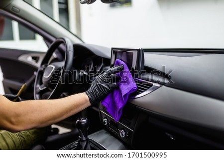 A man cleaning car interior, car detailing (or valeting) concept. Selective focus.  Royalty-Free Stock Photo #1701500995
