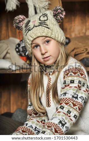 blonde girl in knitted clothes and a hat with pompons