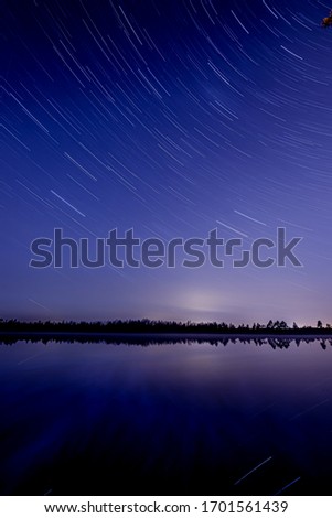 A starry sky at night in the forest on a beautiful lake.