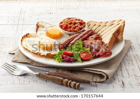 English breakfast with fried eggs, bacon, sausages, beans, toasts and fresh salad Royalty-Free Stock Photo #170157644