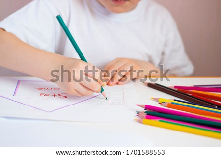 Children's hand holds a colored pencil. Children's drawing. Home leisure for the child.