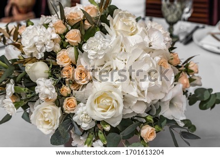 Bride's bouquet of white and yellow flowers on wedding arrangement in restaurant. Bridal bouquet of white and yellow peonies and roses on the table in the restaurant. Awesome wedding table decoration