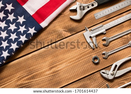 Labor day. American flag and various tools on a wooden background. The concept of labor day. Empty space for text