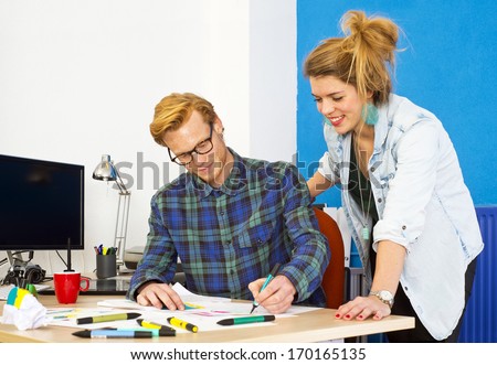 Two creative designers, working on a product innovation, developing ideas and brainstorming together behind a desk in a design studio