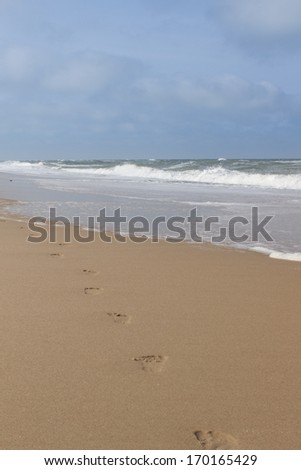 Track of human footprints leading into the horizon. Picture taken at sandy beach during summer time.