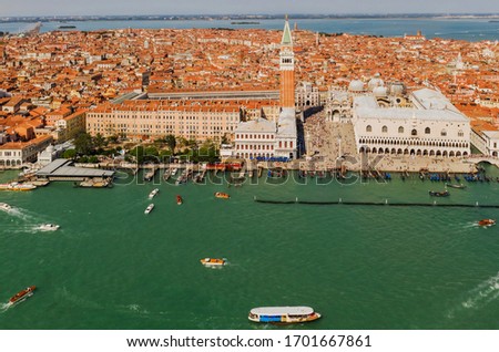 Aerial panoramic shot of Venice city and Grand Canal, Italy. View from above. Tiled roofs and nerros streets. Venetian atmosphere. Blue sky and lagoon water. Historical buildings.