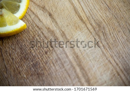 two isolated pieces slices of lemon half in the corner on a wooden chopping board wooden table wooden desk yellow citrus tropical fruit sour raw ingredient fresh cut round citron citric acid flat lay