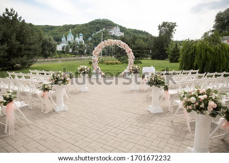 Place for wedding ceremony outdoors, copy space. Circle wedding arch decorated with flowers and chairs on each side of archway. Wedding setting