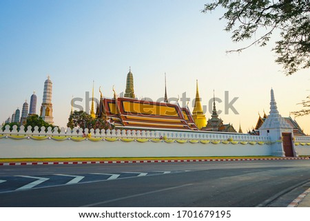The Emerald Buddha temple or Wat Phra Kaew and the Grand palace at sunset, famous tourist attraction of Bangkok, Thailand, with no visitors and empty road Royalty-Free Stock Photo #1701679195