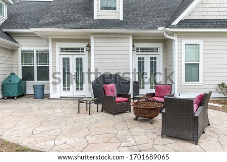 The back rear view of a new construction home with a covered up barbecue and patio furniture with a stamped concrete patio floor Royalty-Free Stock Photo #1701689065