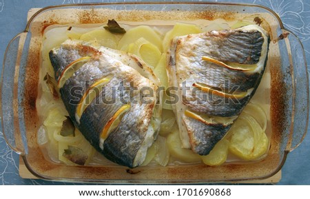 gilthead sea bream fish backed with potatoes and lemons on a dish