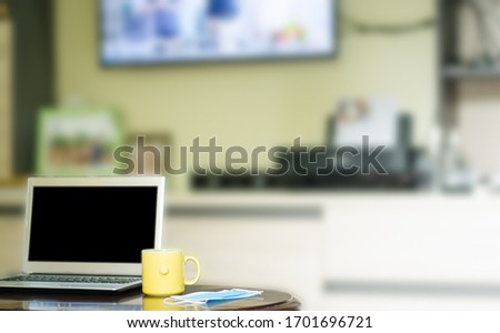 Hot coffee cup with a mask and a laptop on a wooden table. The idea of ​​working at home.
