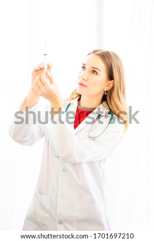 The female doctor is preparing the syringe for injecting the patient in the examination room, backdrop of white curtains in the hospital or clinic.
