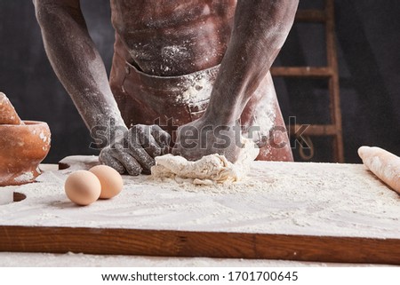 Dark skin baker man kneads Dough in the kitchen. Pastry chef prepares yeast dough for pizza pasta. 