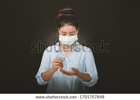 A picture of a girl in the studio wearing protection face mask against Resist infection coronavirus and Cleaning her hands with sanitizer gel.