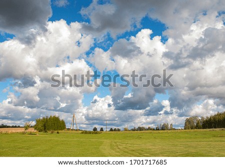 large rain white clouds in the sky above a green field