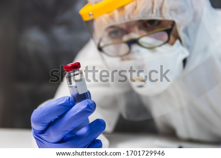 biologic risk.an expert doctor in disease control protected with mask, gloves and visor looks at the coronavirus vaccine.Global pandemic