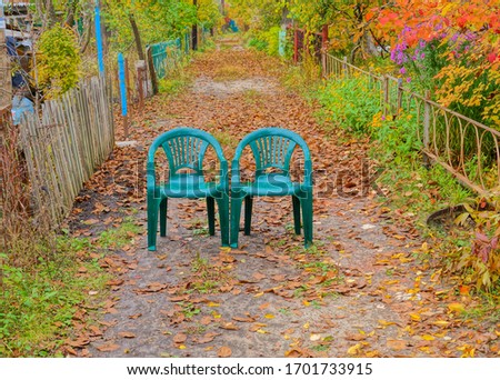       Two green plastic chairs stand on a dirt path amid the colorful fall foliage of an old park on a cloudy day.
Average plan                         