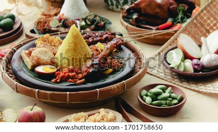 Indonesian tumpeng nasi kuning with complete condiments including petai, grilled chicken, noodles, tempe, satay all in one picture Royalty-Free Stock Photo #1701758650