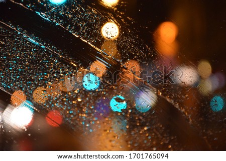 Looking through a rainy car window in a lightfull city.