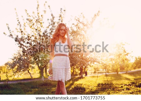 Red-haired model posing on a sunset background.