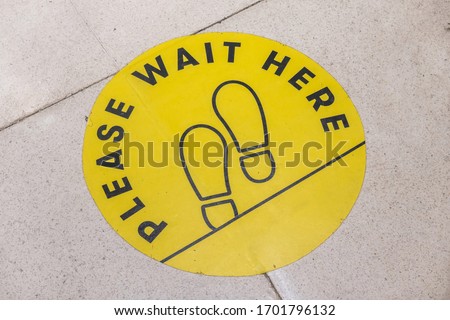 footprint sign for stand in shopping mall, supermarket. Social distancing with COVID-19 coronavirus crisis. yellow footprint sign with text caution social distance Royalty-Free Stock Photo #1701796132