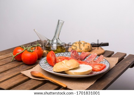 typical Andalusian breakfast, based on tomato bread, ham and oil, on a wooden table