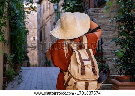 a young woman with hat and traveler backpack is making photos on